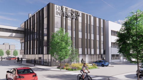 An artists impression of what the building will look like. It is a grey and black striped building with lots of windows spanning the width. It reads 'Hull Royal Infirmary'. There is both a tree and a patch of grass in front of it, and cars are driving past. There are also people walking about, and one man is cycling. 