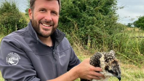 Paul Morton in a grey fleece holding an osprey