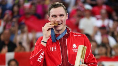 Viktor Axelsen bites his Olympic gold medal