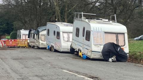 A line of five caravans, all of them white, parked on The Downs in Bristol