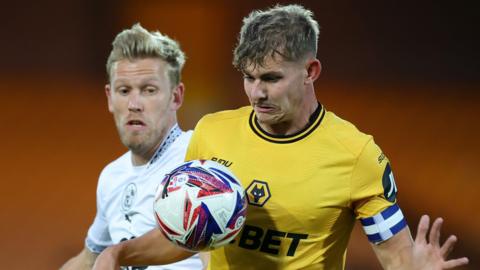 Alfie Pond, playing against Port Vale, for Wolves' Under-21. He is shielding the ball from an opponent with the ball at chest height with his arms out either side. 