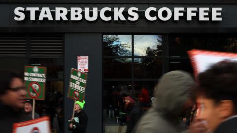 People hold signs outside of a Starbucks Coffee store.