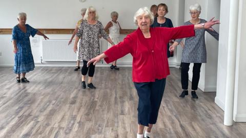 95-year-old tap dancing teacher Joy Saunders shows off some of her moves during a class in Penzance with seven women dancing behind her.