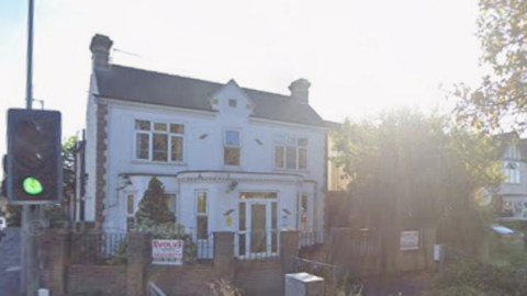 Crossways House is a large, detached building. It is white and has a large porch on the front door with windows either side and on the first floor. There are traffic lights very close to the house