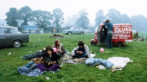 Archive image of a group of people sitting on the grass near Glastonbury Festival.