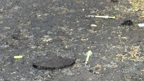 Shows two syringes on the ground