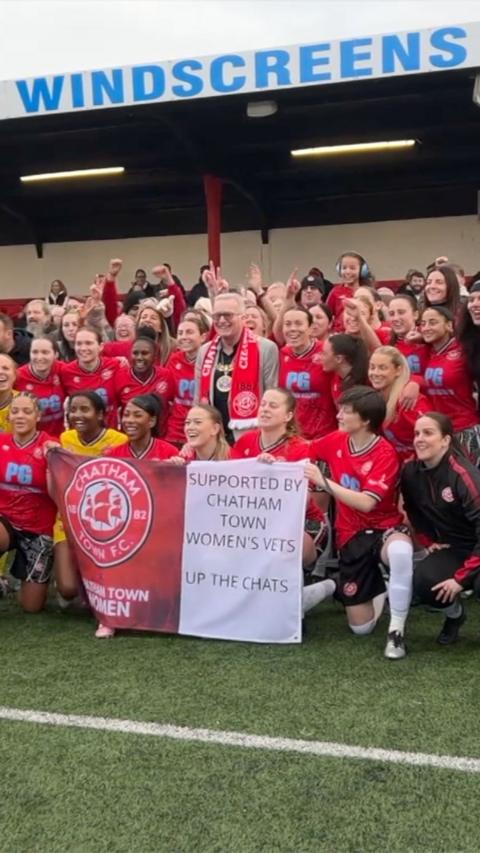 Women in red kit celebrate and pose in a football stadium 