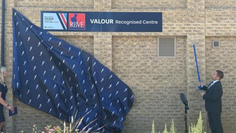 Two people unveiling a plaque which reads Valour Recognised Centre.