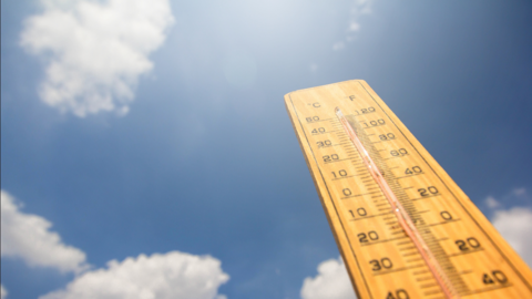 Thermometer against a blue sky with white clouds