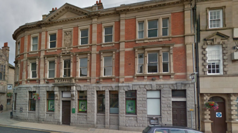 Lloyds bank in Hexham which is a granite building which shapes around a corner. It's a three storey Georgian building with a big door and lots of windows 