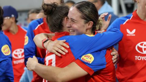 Alice Capsey is hugged by a team-mate