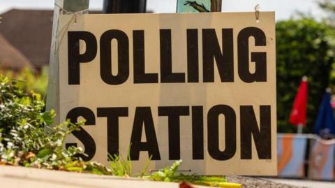 A black and white sign reads polling station in bold capital letters. 