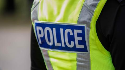 Police jacket in yellow with blue and white police logo.