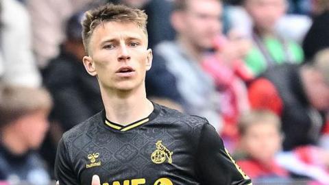 Kristoffer Lund in action for Bundesliga club FC Cologne. He is wearing a black away shirt.