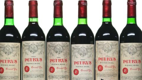 Green bottles of wine with red wax-sealed tops and the branding "Petrus"