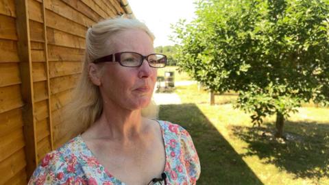 Dr Lorna Mountford gives a TV interview next to a tall wooden fence in a garden. She has 