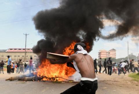 Demonstrator stands in front of burning tyre in Nanyuki, Kenya