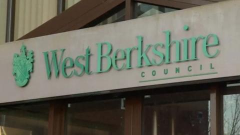 A building entrance with the words West Berkshire Council written in green text on a grey backgrond