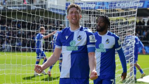 Bristol Rovers midfielder Richie Smallwood celebrates with both fists clenched behind the goal after watching Rovers score in a League Two match