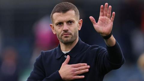 Jack Wilshere raises his hand in thanks to the fans