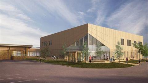 An artist's impression of Deal's new leisure centre, a light brown building with a triangular glass front entrance and landscaped garden in front of it.