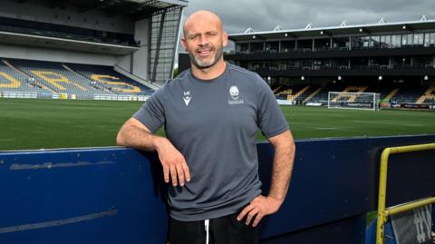 Worcester Warriors head coach leans on a hoarding at Sixways