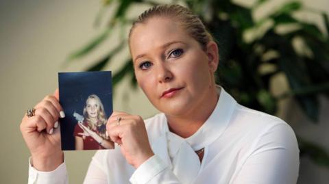 Virginia Giuffre holding a picture of herself as a teenager