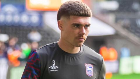 Leif Davis walks back to the dressing room after a pre-match warm-up