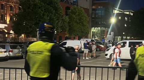 Police standing near men walking hotel at night