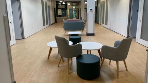 A waiting area at the new healthcare centre. There are a few chairs, tables and sofas.