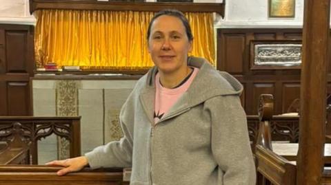 Nikki Dilorenzo, a woman wearing a tracksuit standing inside a church