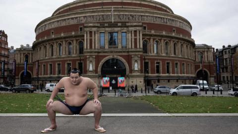 Sumo wrestler wrestler Kitanowaka Daisuke performs a sumo squat outside the Royal Albert Hall.