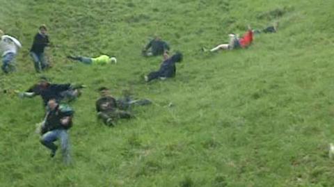 People slide down Coopers Hill.