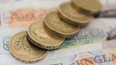 Sterling coins lying on top of one another in a line on top of English bank notes