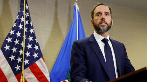 Special counsel Jack Smith, wearing a blue suit, white shirt and blue tie, stands at a podium after a grand jury returned an indictment of former U.S. President Donald Trump in the special counsel's investigation of efforts to overturn his 2020 election defeat