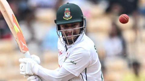 Shakib Al Hasan holds a cricket bat and watches the ball