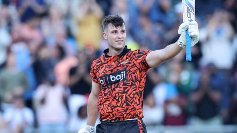 Jordan Hermann holding his bat in the air while standing on the pitch during a match for Surisers Eastern Cape