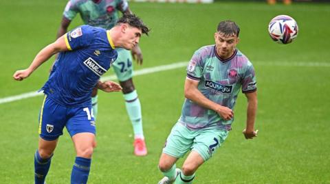 Matty Stevens scores a header for AFC Wimbledon against Carlisle United