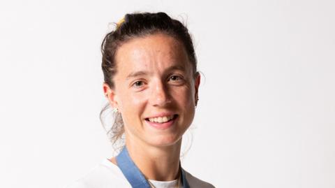 Olympic champion rower Imogen Grant smiles at the camera with her Paris gold medal around her neck
