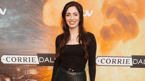 Julia Goulding smiling and standing in front of Corriedale branded backdrop