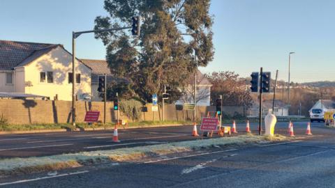 A road with temporary traffic lights in Street. The sun is shining and the sky is blue.