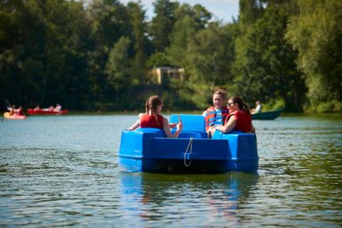 A family out in a pedalo on the water of a loch with trees in the background