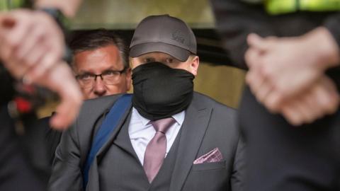 Former funeral director Robert Bush leaves Hull Crown Court, he is wearing a grey three piece suit with a purple tie and pocket square. 