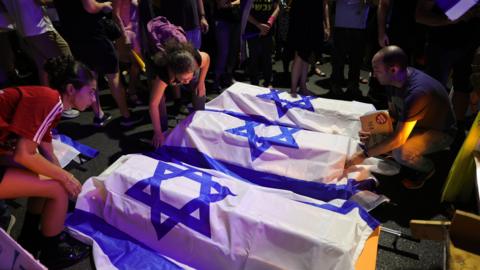 Protesters supporting the families of Israeli hostages held by Hamas in Gaza, place six mock-coffins outside the residence of Prime Minister Benjamin Netanyahu