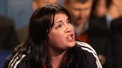 Suzanne Vjestica-Brown has long dark hair and is shouting instructions to a fighter.