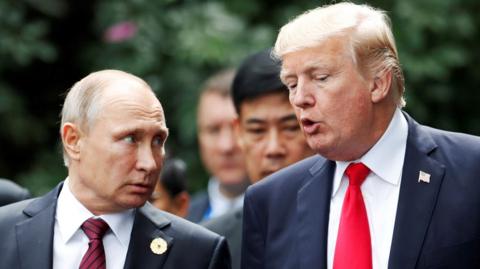 U.S. President Donald Trump and Russia"s President Vladimir Putin talk during the family photo session