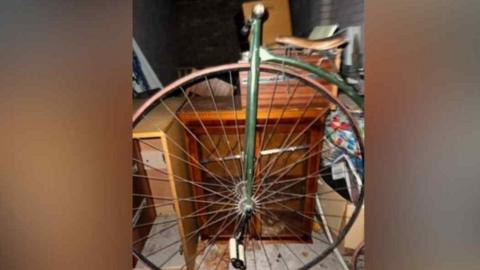 The bicycle, propped up against old furniture in a small storage space