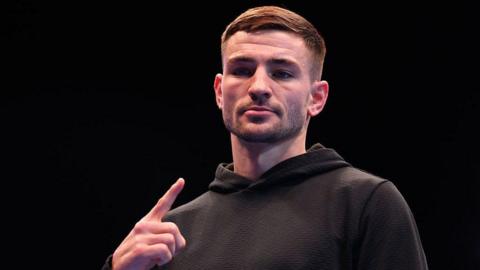 Sam Noakes, in a black hoodie, poses for a photo during a Ring IV: Night of the Champions Workout ahead of his WBO World Lightweight title fight against Abdullah Mason.