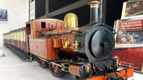 A model of the No 16 locomotive Mannin, which is painted in light brown with gold trim and a black front. It's sitting on a table in the exhibition.