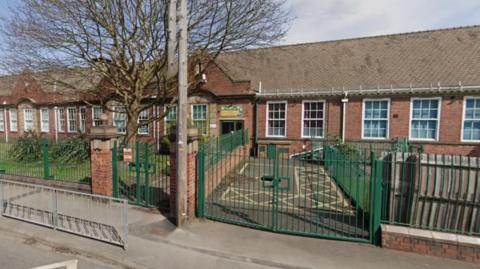 An old style primary school with green railings and white frame windows.